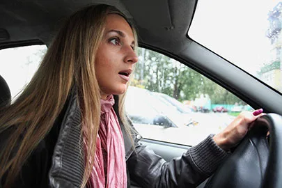 Junge Frau am Steuer blickt angespannt durch die Windschutzscheibe