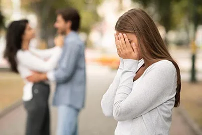Frau verbirgt weinend ihr Gesicht, im Hintergrund umarmt sich ein Paar