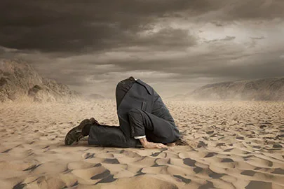 Mann im Anzug steckt den Kopf in den Sand, Wüstenlandschaft mit dramatischem Himmel