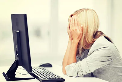 Frau sitzt verzweifelt vor dem Computer und verbirgt ihr Gesicht in den Händen